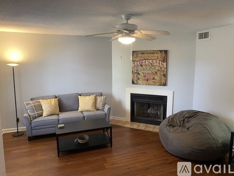 A living room with a grey couch, a fireplace, and a painting on the wall.