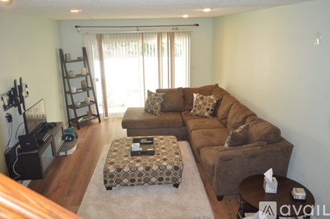 A living room with a brown couch and a patterned ottoman.