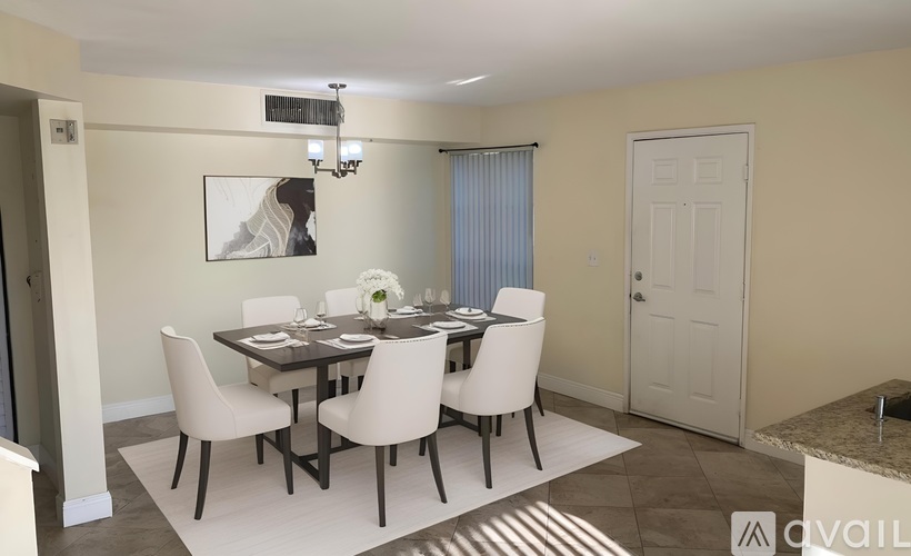 A dining room with a table set for six and a painting on the wall.
