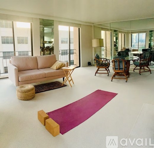 A living room with a pink rug and wooden furniture.