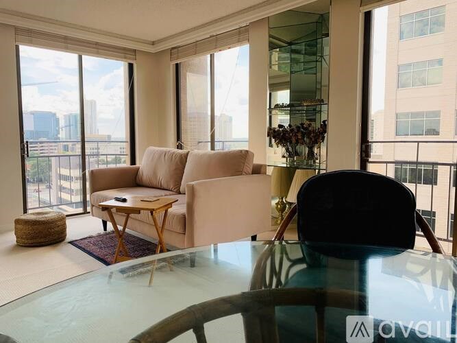 A living room with a glass table and a view of the city.
