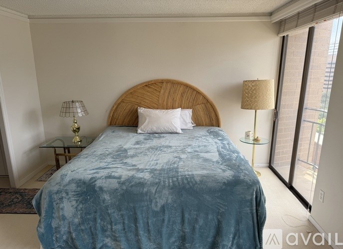 A bed with a blue comforter and a wooden headboard is in the image.