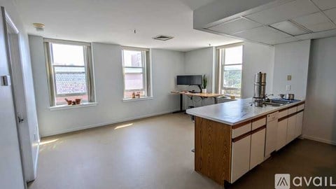 A spacious kitchen and living room with a television and large windows.