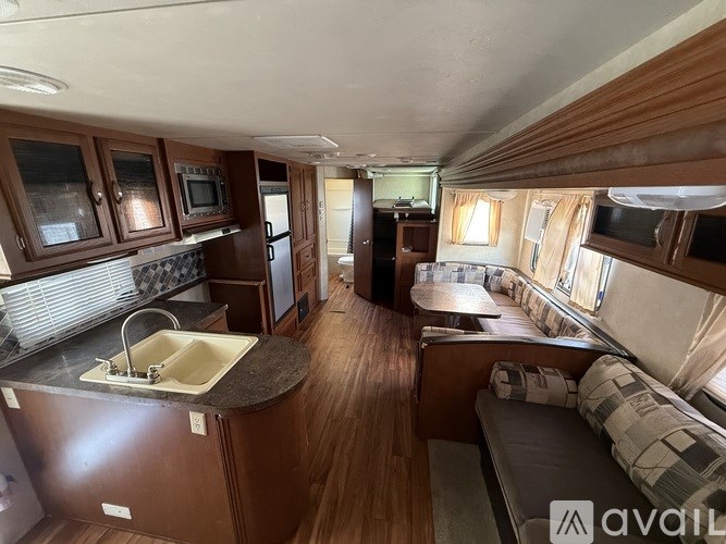 A well-lit interior of a trailer with a kitchen area and a living room.