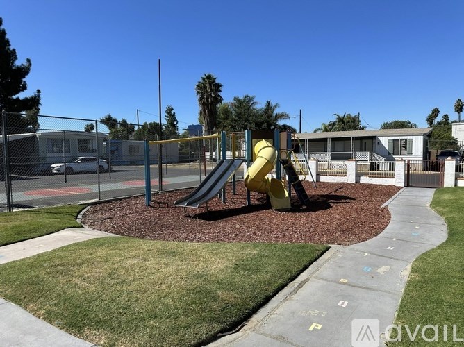 A playground with a yellow slide and a fence.