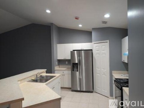 A kitchen with a stainless steel refrigerator and white cabinets.