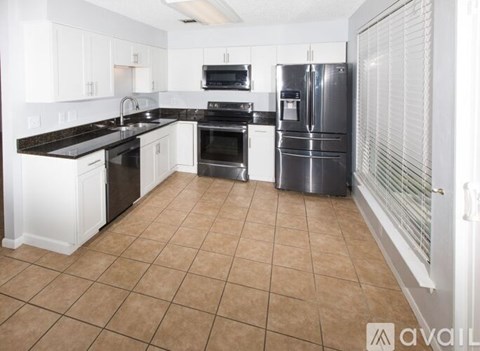 A kitchen with white cabinets and a black countertop.