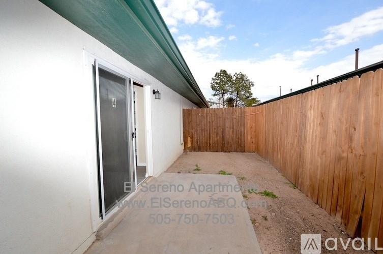 A white building with a green roof and a wooden fence.