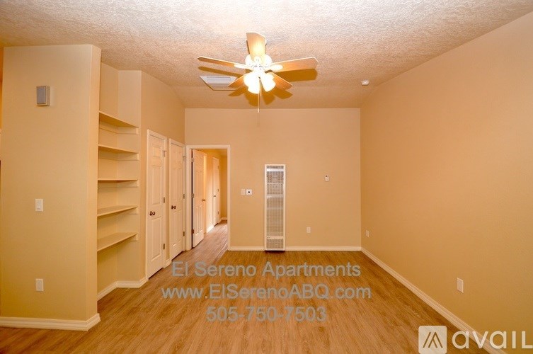 A spacious apartment living room with a ceiling fan and built-in shelves.