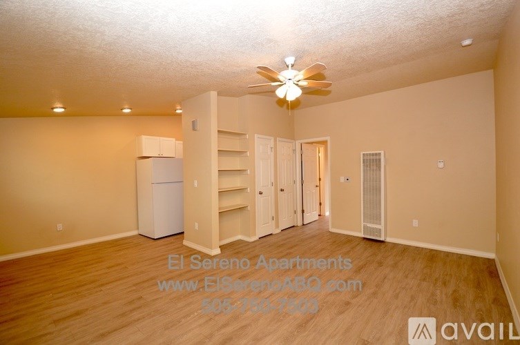 A well-lit, empty apartment with a ceiling fan and a refrigerator.