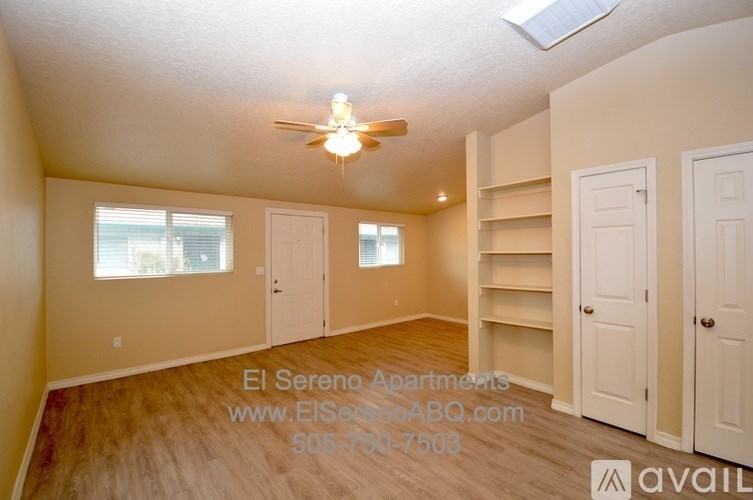 A well-lit, empty apartment with a skylight and a fan on the ceiling.