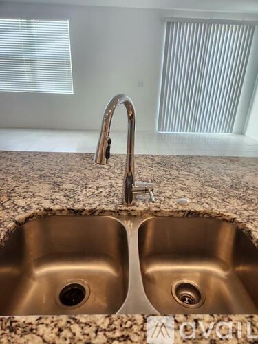 A modern kitchen sink with a granite countertop and a chrome faucet.