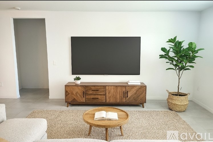 A living room with a flat screen TV mounted on the wall above a wooden cabinet.