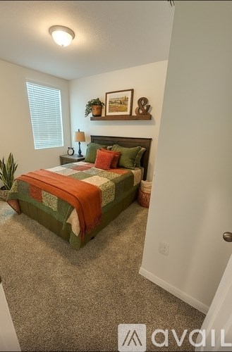 A bedroom with a bed, lamp, and pictures on the wall.
