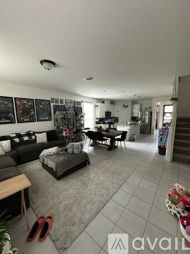 A living room with a black couch, a grey rug, and a dining table with chairs.