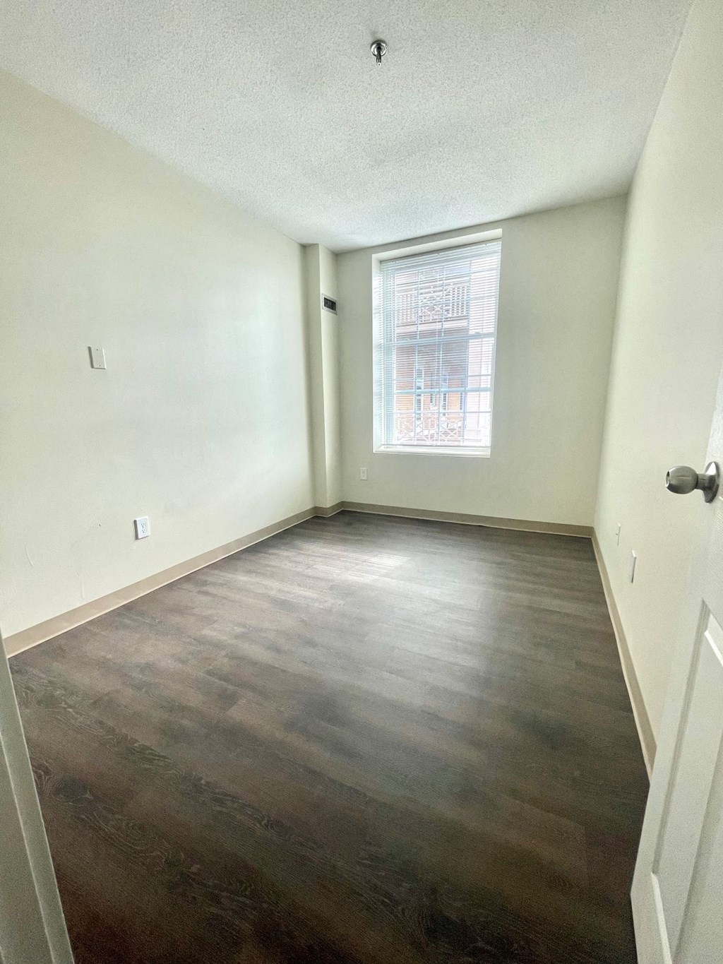 an empty room with wood flooring and a window