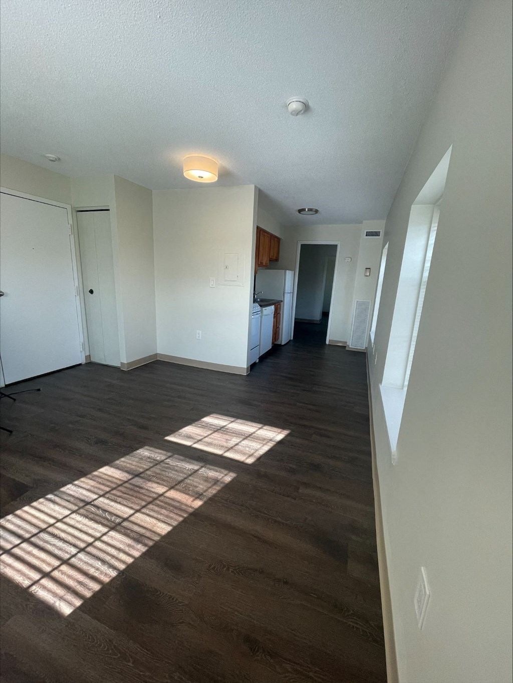 an empty living room with hardwood floors and a kitchen