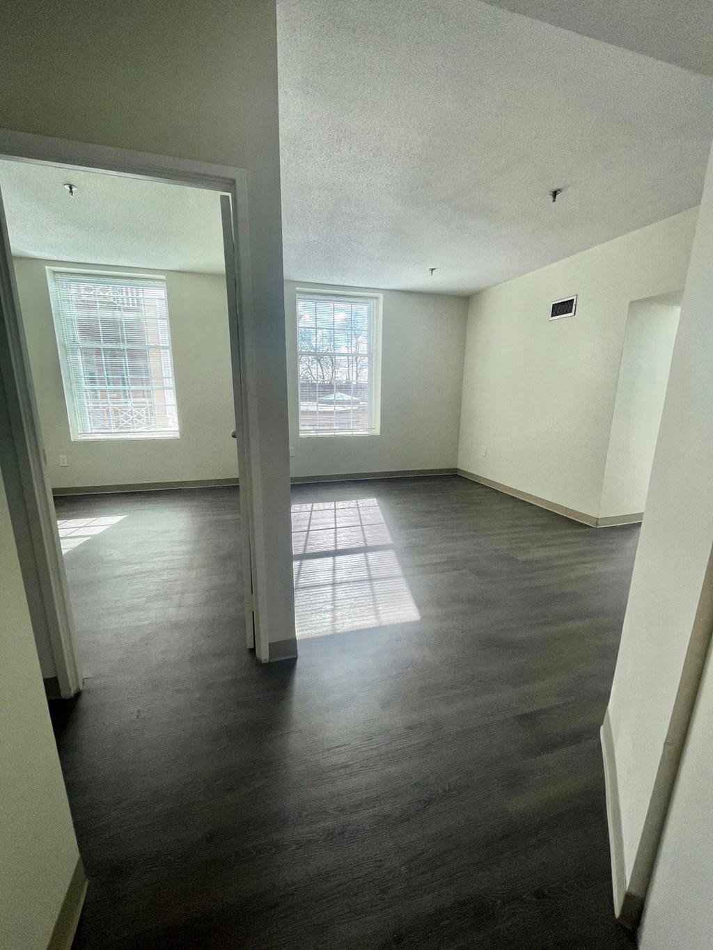an empty living room with wood floors and white walls
