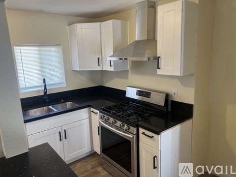 A kitchen with white cabinets and black countertops.
