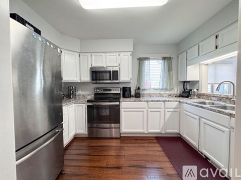 A kitchen with white cabinets and a wooden floor.