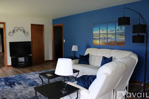 A living room with a white couch and a painting on the wall.