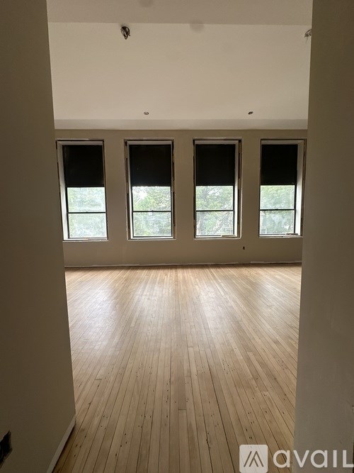 A room with wooden floors and three windows.