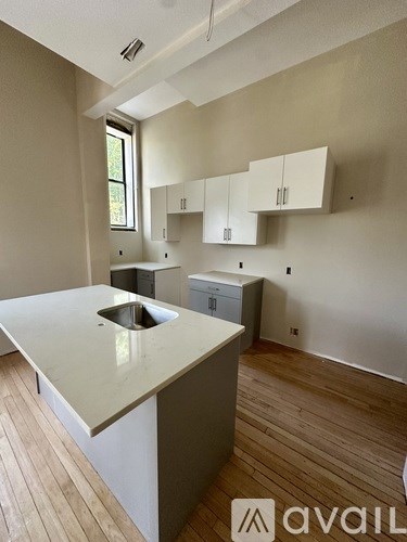 A room with wooden flooring and three windows.