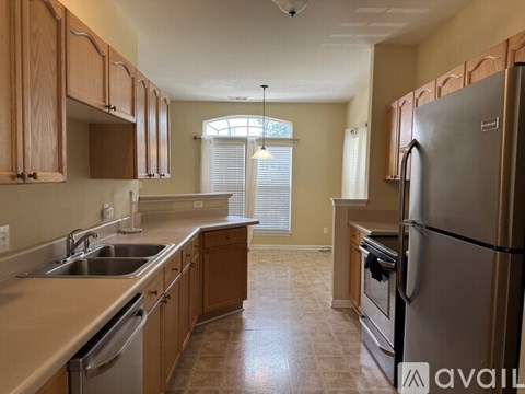 A kitchen with wooden cabinets and a stainless steel refrigerator.