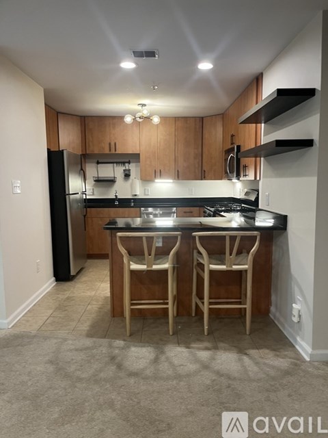 A kitchen with a black fridge and a black stove top oven.