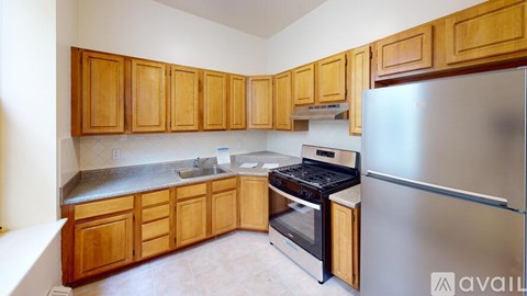 A kitchen with wooden cabinets and a stainless steel refrigerator.