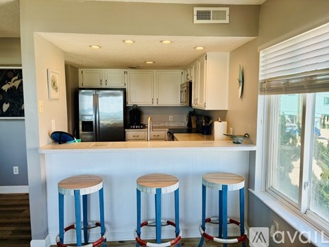 A kitchen with white cabinets and a blue bar stool.