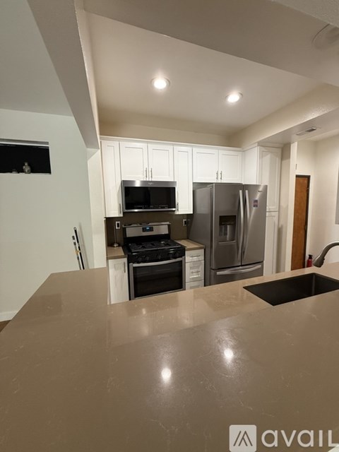A kitchen with a refrigerator, oven, and sink.