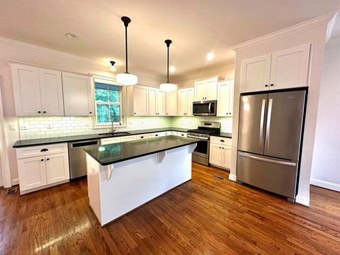 A kitchen with white cabinets and a black island.