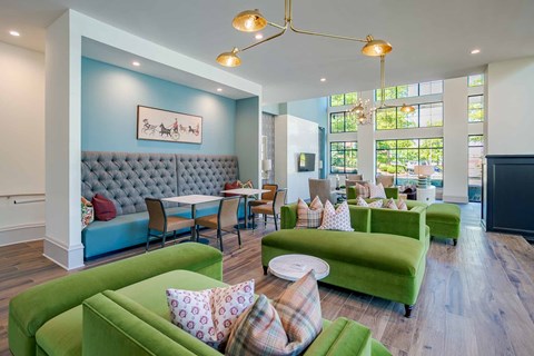 A living room with a grey tufted couch and green couches.