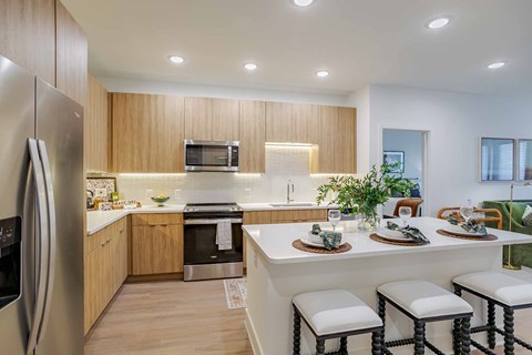A modern kitchen with a refrigerator, microwave, oven, and a dining table set for two.