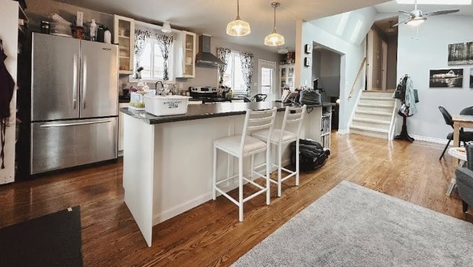 A kitchen with a refrigerator, sink, and dining table.