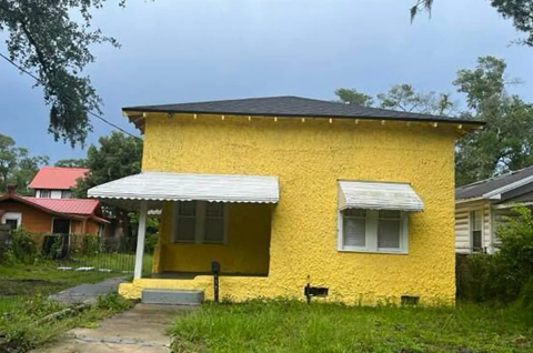 A yellow house with a red roof in the background.