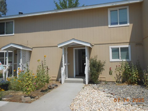 A beige house with a gravel path leading to the front door.