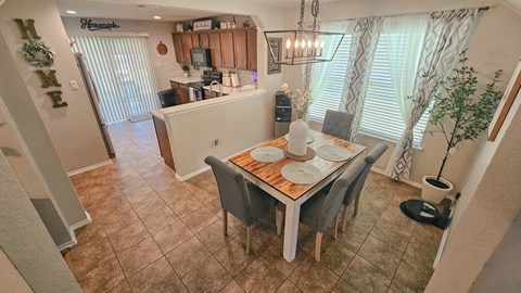 A dining room with a table set for two and a kitchen area in the background.
