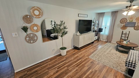 A living room with a wooden floor and a flat screen TV mounted on the wall.