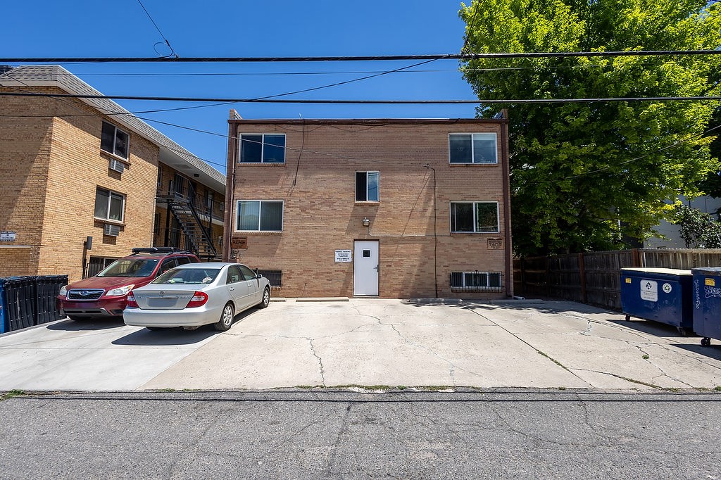 A red car is parked in front of a brick building.
