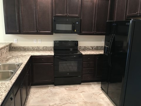 A black oven and microwave in a kitchen with brown cabinets.