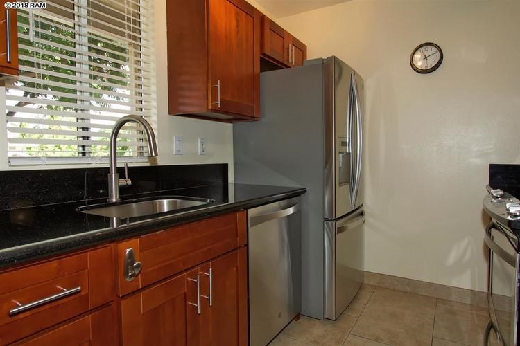 A kitchen with a refrigerator, sink, and cabinets.