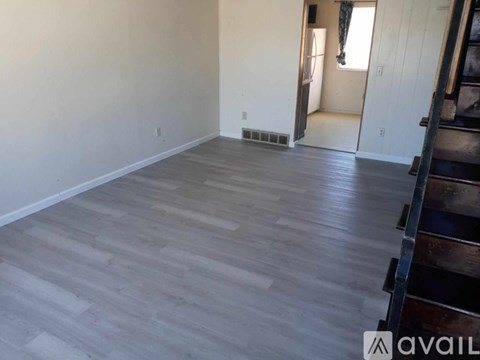 A room with wooden flooring and a doorway leading to another room.