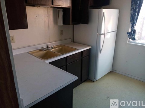 A kitchen with a sink, refrigerator, and cabinets.