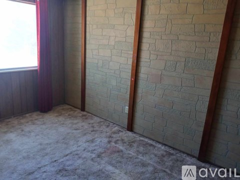 A room with a brick wall and a window with red curtains.