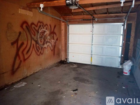 A garage with a white door and graffiti on the wall.