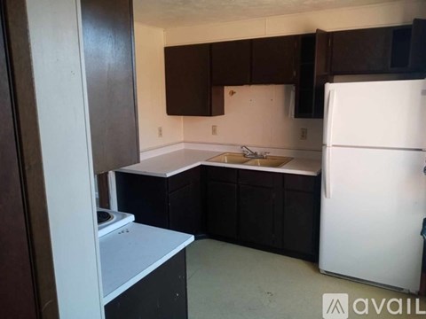 A kitchen with brown cabinets and a white fridge.