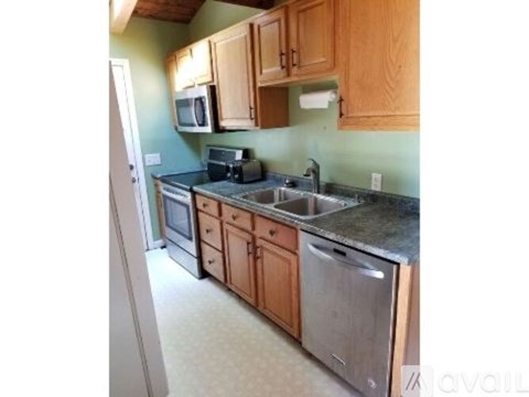 A kitchen with wooden cabinets and a stainless steel dishwasher.