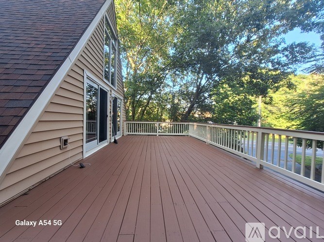A wooden deck with a house and trees in the background.